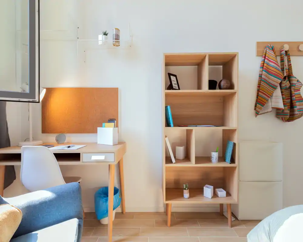 Bright, modern living area with a small desk, shelving unit and comfortable seating — ideal for working and relaxing in a sunlit space.