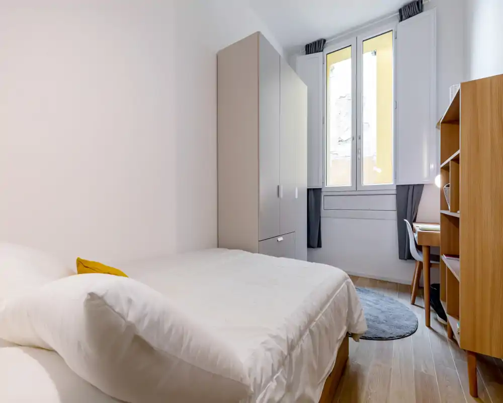 Dormitorio individual luminoso y bien presentado con cama cómoda, armario, escritorio y luz natural de una ventana grande — ideal para estudiante o inquilino solo.