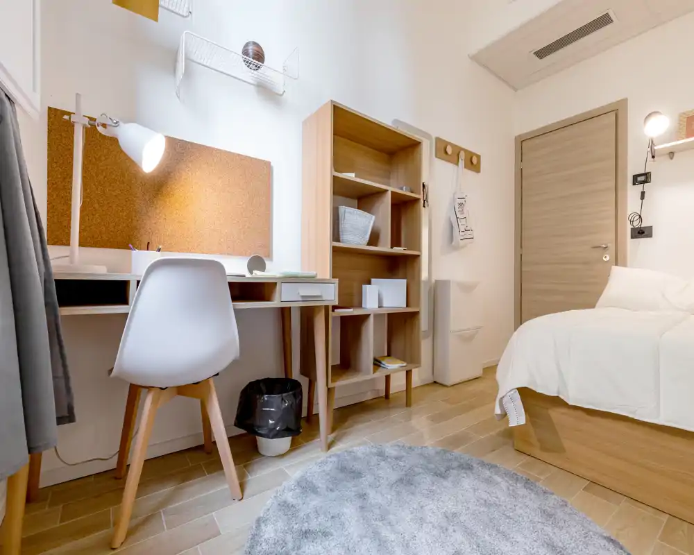 Dormitorio luminoso y bien decorado con cama individual, muebles de madera y escritorio — ideal para estudiantes o estancias cortas.