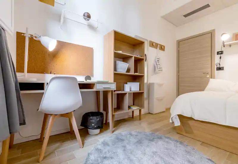 Dormitorio luminoso y bien decorado con cama individual, muebles de madera y escritorio — ideal para estudiantes o estancias cortas.