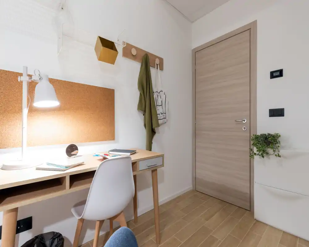 Zona de entrada ordenada con una mesa y silla junto a una puerta interior de madera; luminosa y minimalista, perfecta para un pequeño vestíbulo o rincón de estudio.
