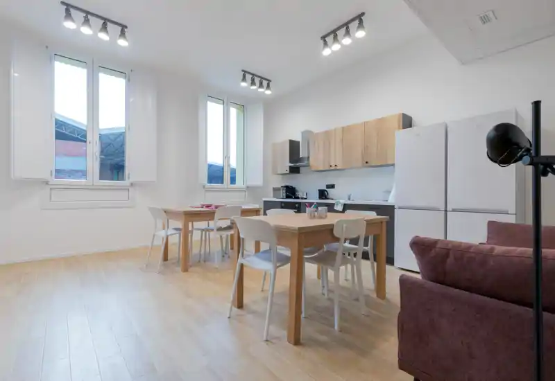 Bright open-plan kitchen with wooden cabinets, a dining table and modern appliances; clean, airy space ideal for short-term rentals.
