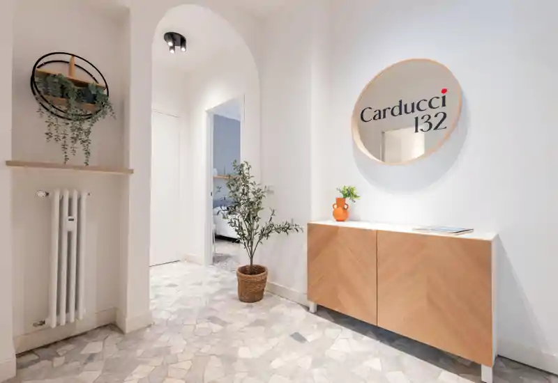 Bright, modern entrance with patterned stone floor, a wooden console, decorative mirror and potted plant creating a welcoming first impression.