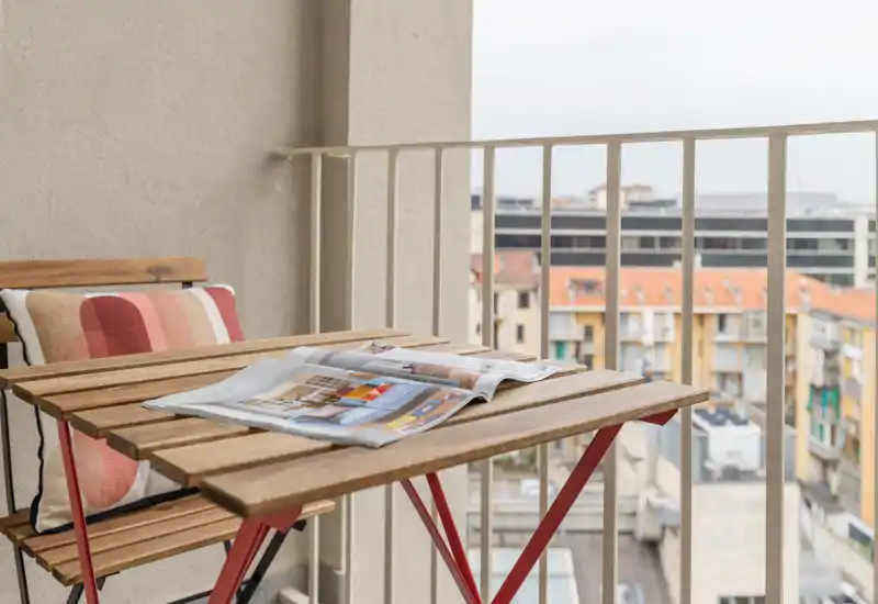 Cozy city balcony with a small wooden bistro table and chair, ideal for morning coffee and enjoying urban views.