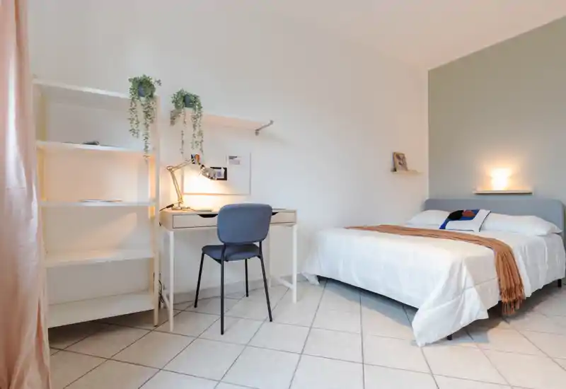 Bright, minimal bedroom with a comfortable double bed, soft textiles and a tidy desk area — ideal for a restful stay and remote work.